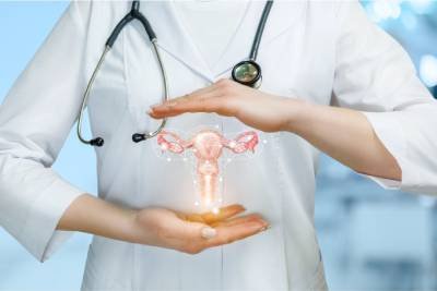 Female doctor protecting holographic uterus with hands – symbolizing gynecological health