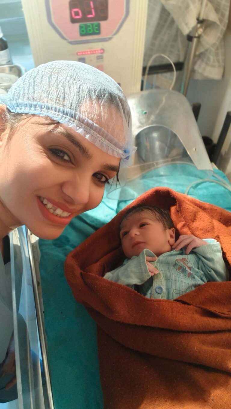 Dr. Archana Mohana, Best Lady Gynecologist in Indore, smiling beside a healthy newborn wrapped in a brown blanket after successful delivery.