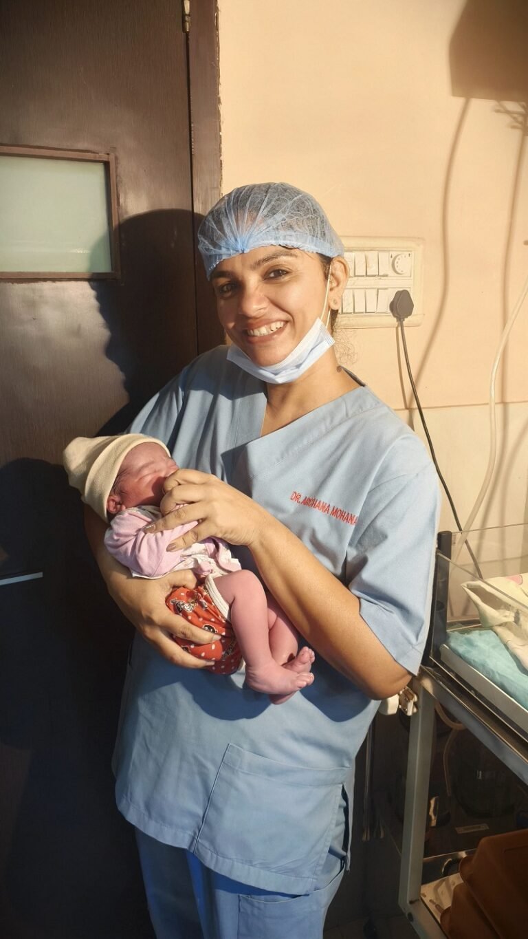 Dr. Archana Mohana holding a newborn baby after a successful delivery in Indore
